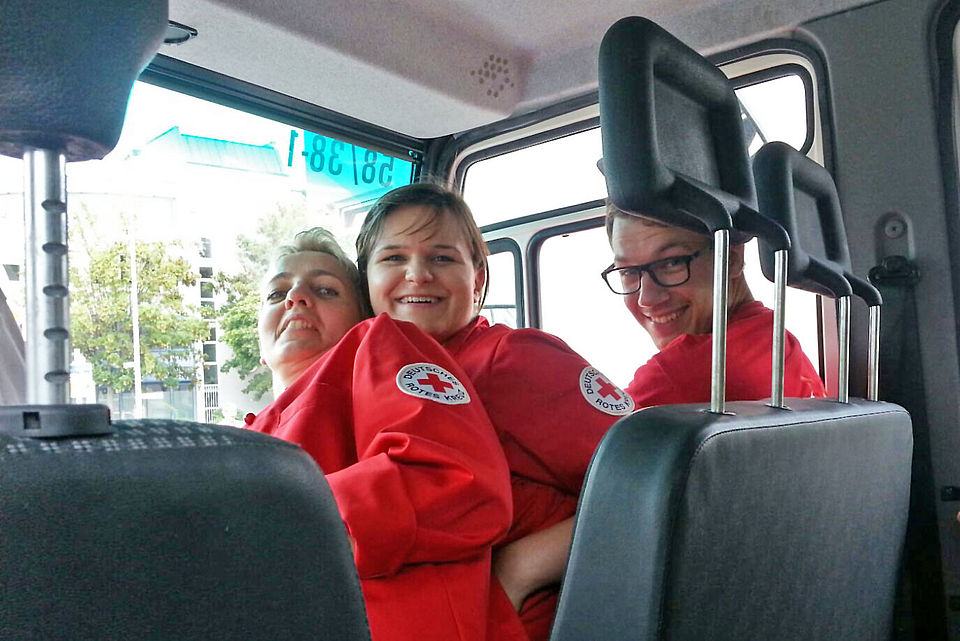 Mitglieder sitzen im Auto und grinsen in die Kamera.